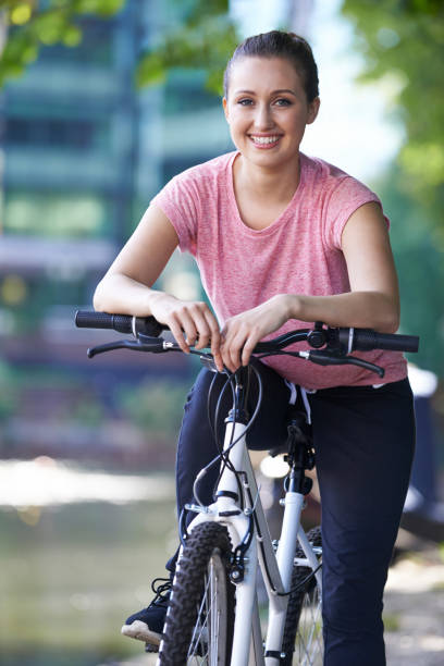 istock Young Woman Cycling Next To River In Urban Setting 846399088