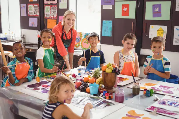 Portrait of smiling teacher and schoolkids in drawing class