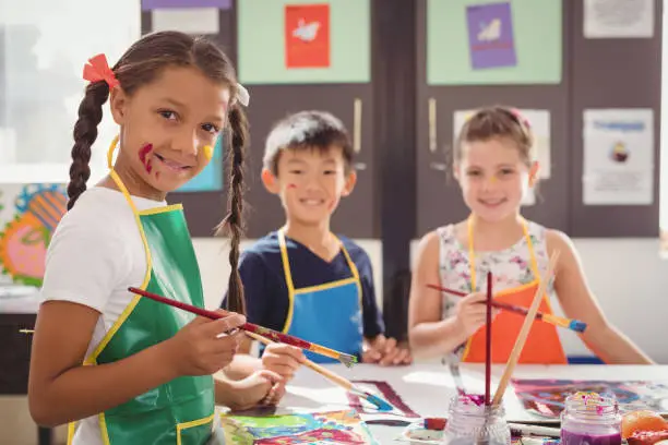 Portrait of happy schoolkids practicing drawing in school