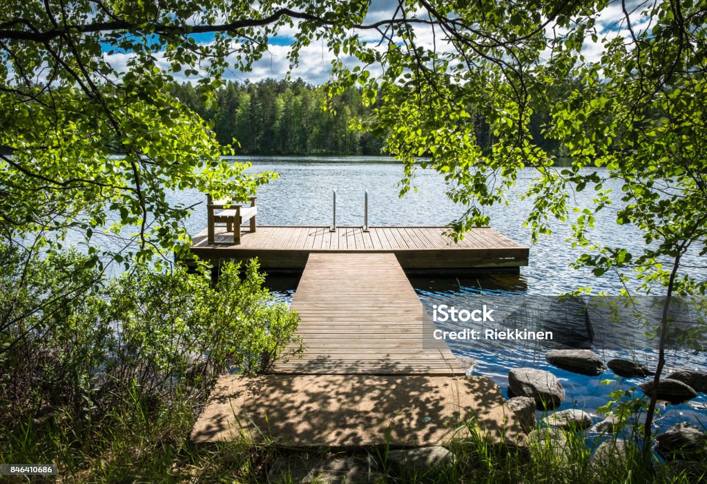 Vista del idílico lago con muelle en día de verano soleado brillante. - Foto de stock de Lago libre de derechos