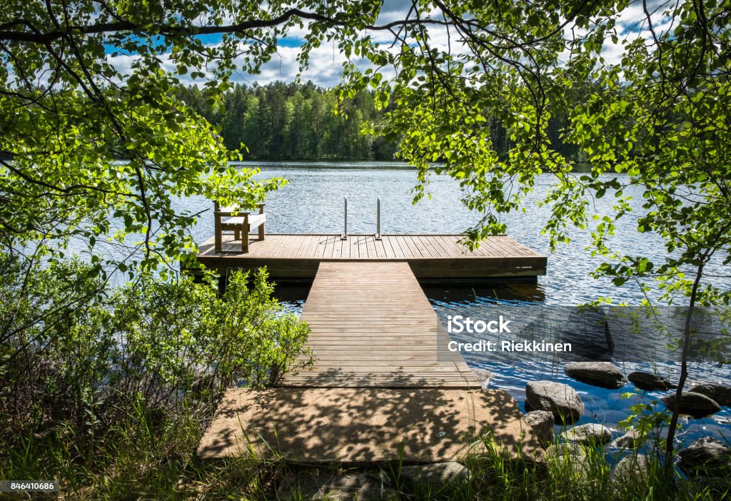 Idyllic lake view with pier at bright sunny summer day. Lake Stock Photo