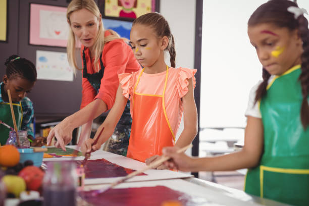 istock Teacher assisting schoolkids in drawing class 846410828
