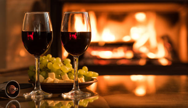 Two red wine wineglasses over fireplace background. stock photo