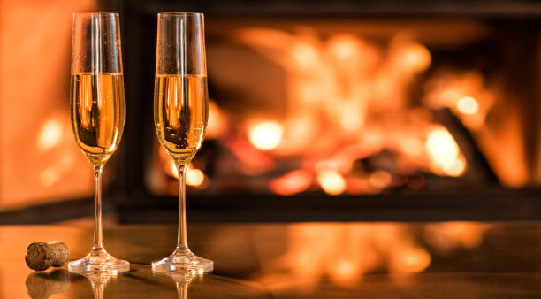 istock Champagne in two glasses on table in front of burning fireplace. 846414530