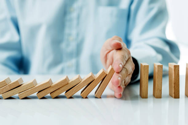 Businessman hand stopping falling blocks on table Businessman hand stopping falling blocks on table domino photos stock pictures, royalty-free photos & images
