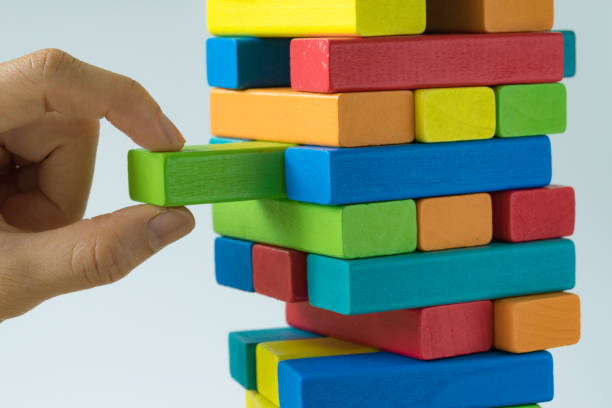 istock Hand pulling colorful wooden block from the tower in as Risk or stability concept 846419124