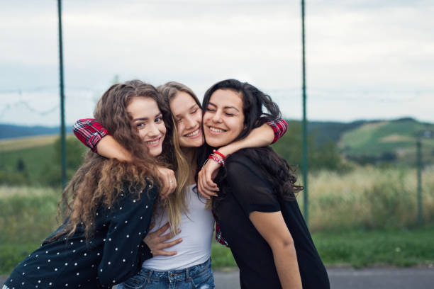 Three attractive teenage girls outdoors on playground. Three attractive teenage girls outdoors on playground hugging. adolescents hanging out stock pictures, royalty-free photos & images