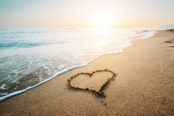 dessin de coeur sur le sable jaune sur le coucher de soleil fantastique - valentines day hearts flash photos et images de collection