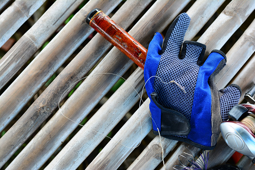 fishing rod ,reel ,blue glove  and black bait  lure on bamboo background