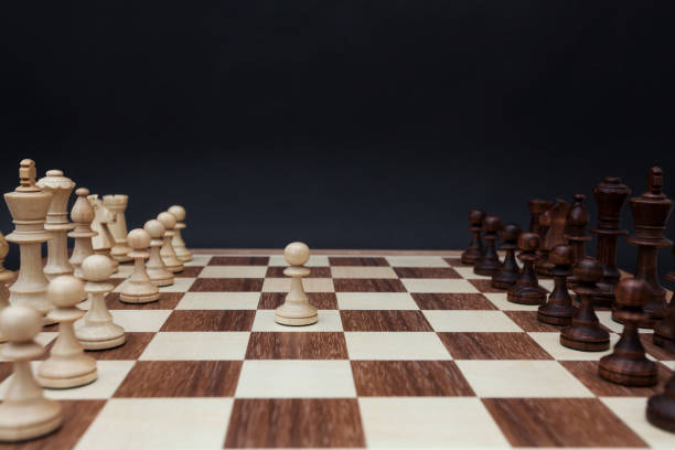 istock First move by white pawn on the center of board. Chess board on a black background 846436706