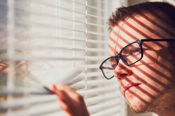 curieux homme regardant à travers une jalousie - optics store photos et images de collection