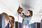Female airplane passenger storing handbag in locker