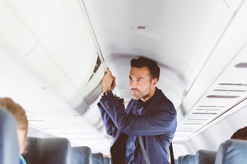 Hombre viaja en vuelo almacenar el bolso en el armario de arriba photo