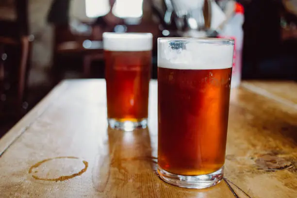 Photo of An english ale bitter beer pint on a wooden table in a pub in UK