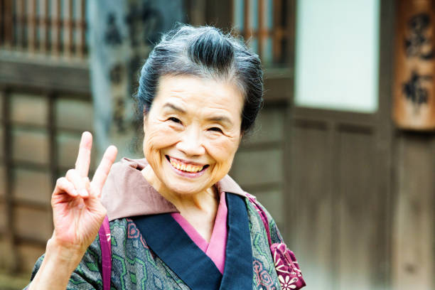 Old Japanese lady in traditional clothing portrait smiling and doing peace sign Old Japanese lady in traditional clothing portrait smiling and doing peace sign in a historical reenactment at Toei studios in Kyoto. actress headshot stock pictures, royalty-free photos & images