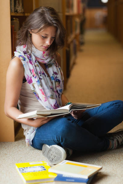 istock Female student reading a book in the library aisle 846465746
