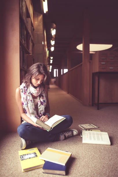 istock Female student reading a book in the library aisle 846465916