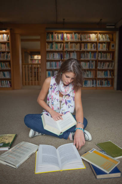 istock Female student sitting with books on the library floor 846466046