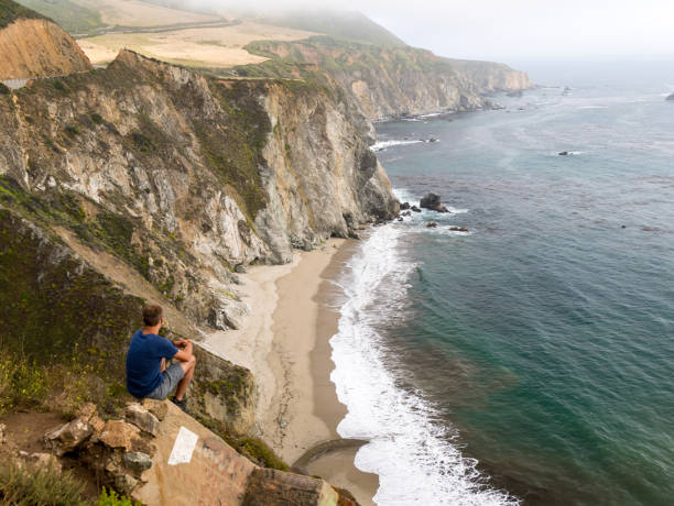 istock Man sitting on viewpoint over californian coast on cloudy mist day 846473188