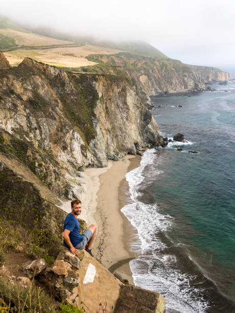 istock Man sitting on viewpoint over californian coast on cloudy mist day 846473190
