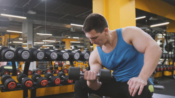 istock Weight-lifting in the gym - muscular athlete performs training for biceps with dumbbells 846478146