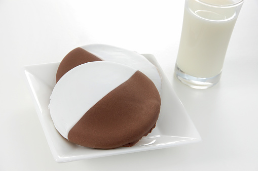 American traditional black and white or half moon cookies served with a glass of cold milk.
