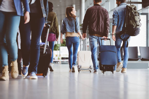 Passengers walking in the airport corridor Passengers walking in the airport corridor with luggage. Travelling people at airport terminal. frequent flyer stock pictures, royalty-free photos & images