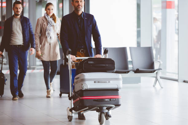 persone che camminano nel terminal dell'aeroporto con i bagagli - baggage wagon foto e immagini stock