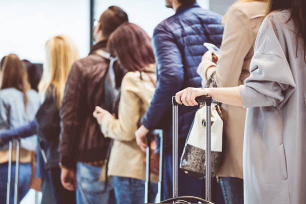 Group of people standing in queue at boarding gate Group of people standing in queue at boarding gate. Focus on female hand holding suitcase handle. airports stock pictures, royalty-free photos & images