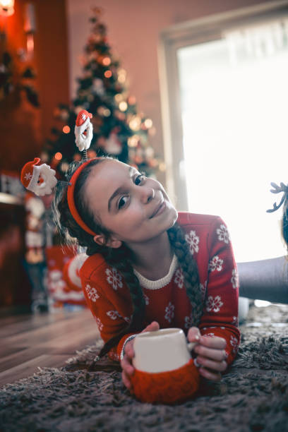 istock Little Girl Lying Under Christmas Tree and Drinking Hot Beverage 846525466