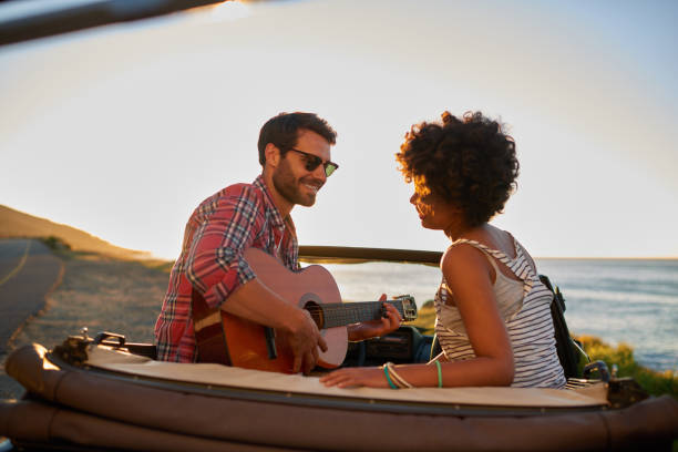 istock Young man playing on guitar during roadtrip 846542504