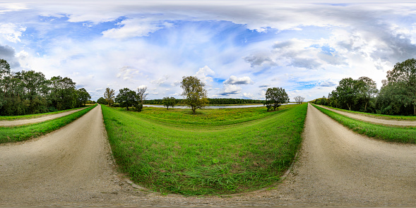 360 degrees spherical panoramic shot of green meadows by the river in the summer afternoon