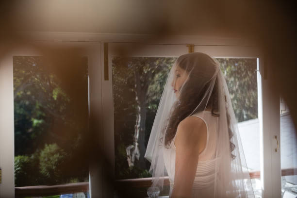 istock Beautiful bride in wedding dress looking through window 846549206