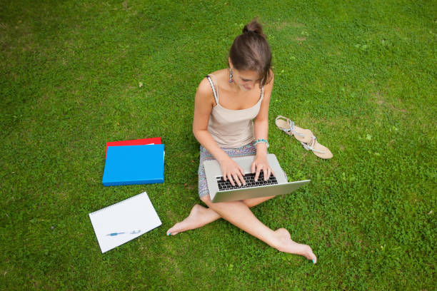 istock Student using laptop with books at the park 846558726
