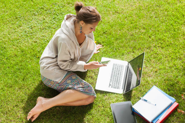 istock Student using mobile phone laptop with books at the park 846558738