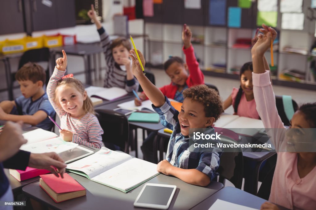 Collégiens, levant leurs mains dans la salle de classe - Photo de Enfant libre de droits