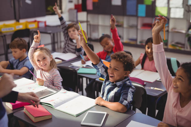 scolari che alzano le mani in classe - child classroom education school foto e immagini stock