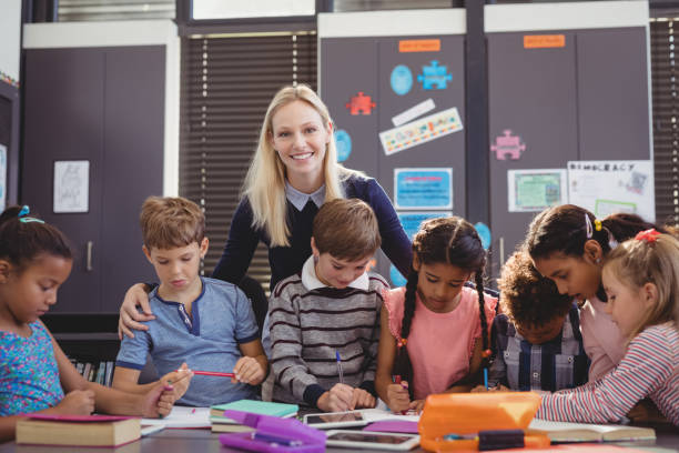 istock Teacher helping schoolgirl with her homework in classroom 846567700