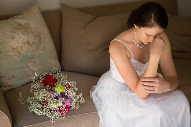 istock Sad bride sitting by bouquet on sofa at home 846573158