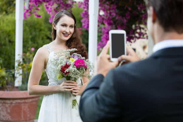 istock Bridegroom photographing bride holding bouquet at park 846590748