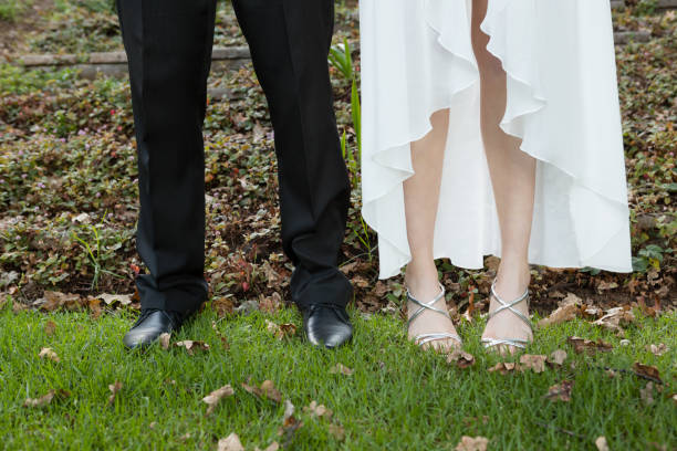 Low section of newlywed couple standing on field