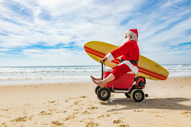 Santa Claus Doing a Wheelie on a Motorised Esky Cooler on the Beach Santa Claus relaxing after Christmas doing a wheelie while riding a motorised esky cooler on the beach cooler container photos stock pictures, royalty-free photos & images