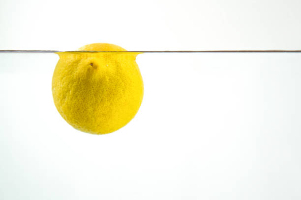 Lemon floats in a water aquarium on a white background.