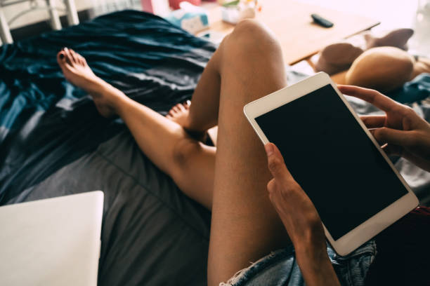 istock Close up of young woman using tablet while sitting on her bed,  Films grain filter. 846632742