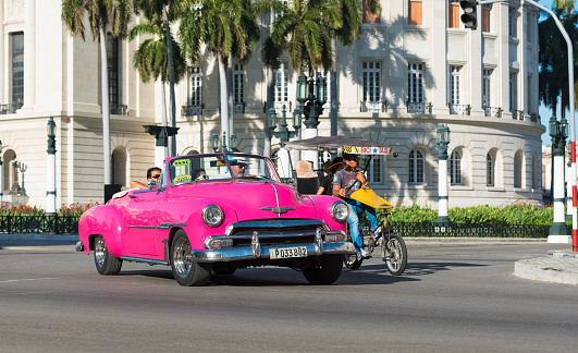 Havana: American pink Chevrolet cabriolet classic car drived on the main street with tourists through Havana City Cuba - Serie Cuba Reportage