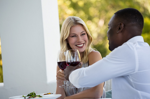 Happy young couple toasting wineglasses while sitting at restaurant