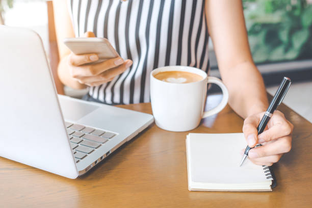 istock Business woman hand is writing a pen notebook and using a phone in office. 846643092