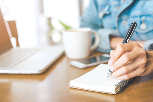 istock A woman's hand working on a notebook computer and writing on a notepad with a pen in the office. 846643096