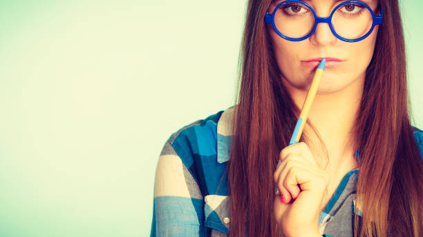 istock Nerdy thinking woman in glasses holding pen 846646398