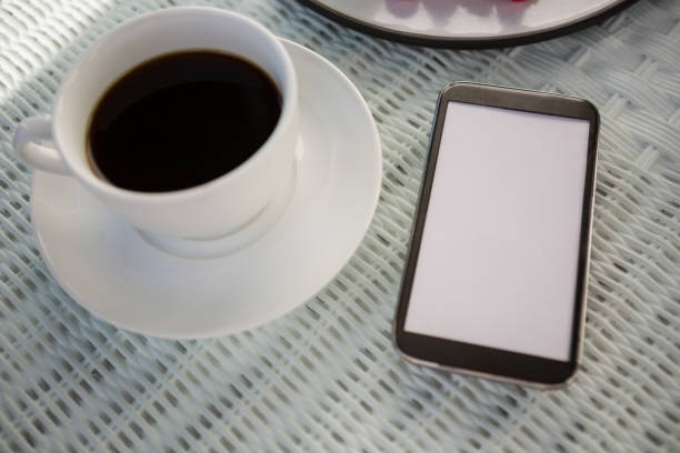 istock Coffee cup by mobile phone on table at cafe 846657242